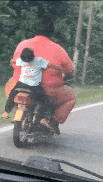 a man in a red shirt is riding a motorcycle with a child in a blue shirt that says zoo princess