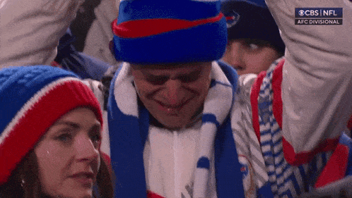 a man in a blue hat and scarf is crying while watching a game on cbs nfl