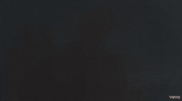 a shirtless man wearing overalls and a necklace with the word vevo on the bottom left