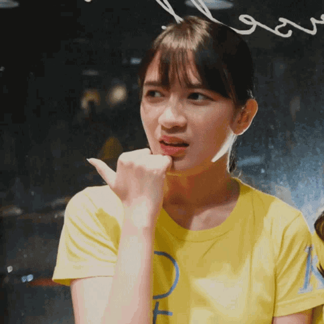 a woman wearing a yellow shirt with the letter t on the front