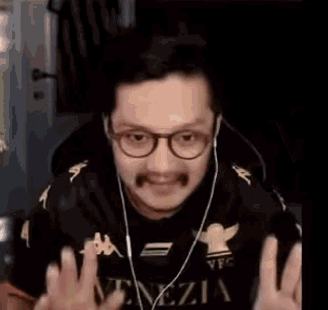 a man wearing glasses and headphones is making a funny face while sitting at a table .