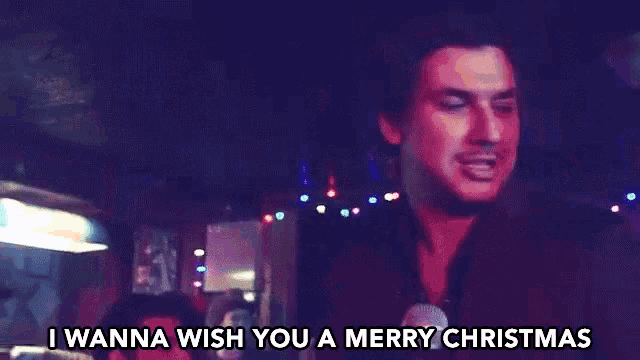 a man singing into a microphone with the words i wanna wish you a merry christmas