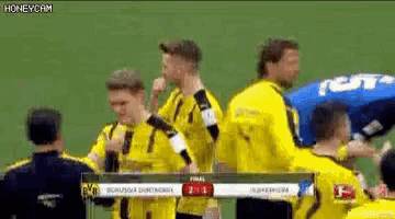 a group of soccer players are standing on a field and one of them is covering his nose