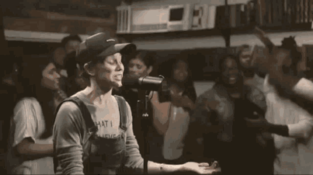 a man is singing into a microphone while standing in front of a crowd of people .