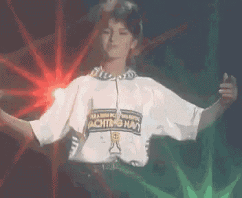 a person is dancing in front of a red light and a green plant .