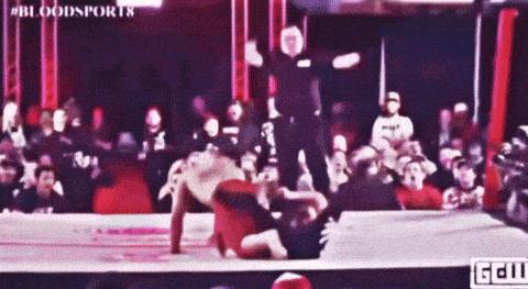 two men are wrestling in a ring with a referee in the background