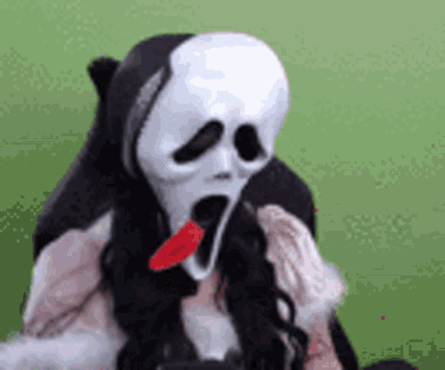a woman wearing a scream mask with a red tongue sticking out of it .