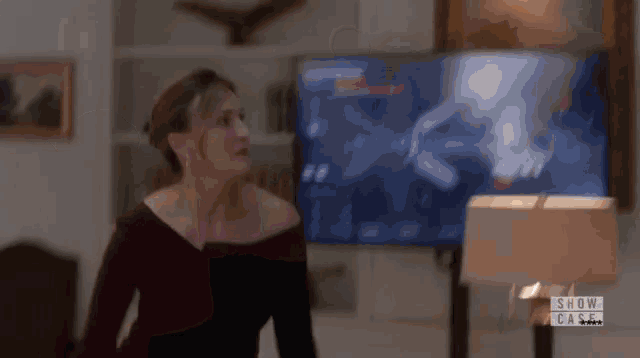 a woman is standing in front of a television that says show case on it