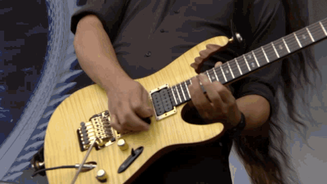 a man with long hair is playing a guitar with a picture in the background