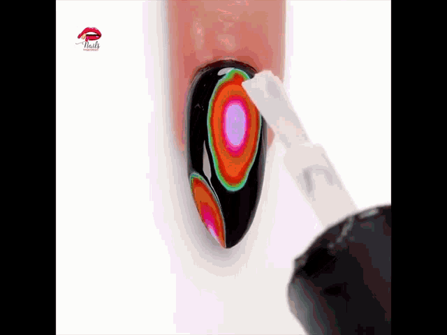 a bottle of nail polish is being applied to a nail with a colorful design on it .