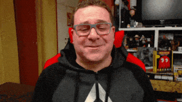 a man wearing glasses is smiling in front of a shelf with pac man toys on it