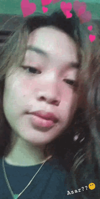 a girl with hearts on her head is wearing a black shirt and a gold necklace .