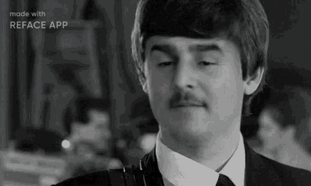 a man with a mustache is wearing a suit and tie and making a funny face .