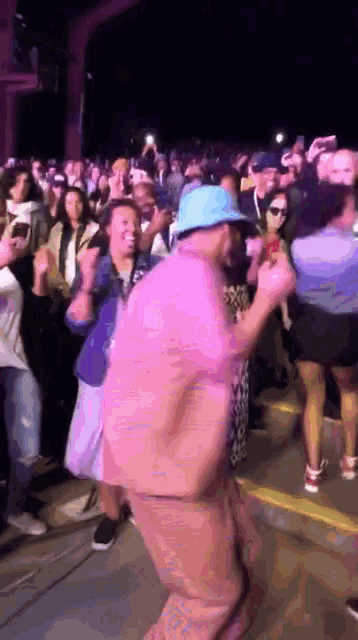 a man wearing a blue hat is dancing in front of a crowd