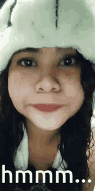 a girl wearing a white hat is making a funny face and says hmm