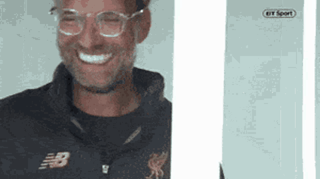 a man wearing glasses and a jacket with the letter b on it is smiling .