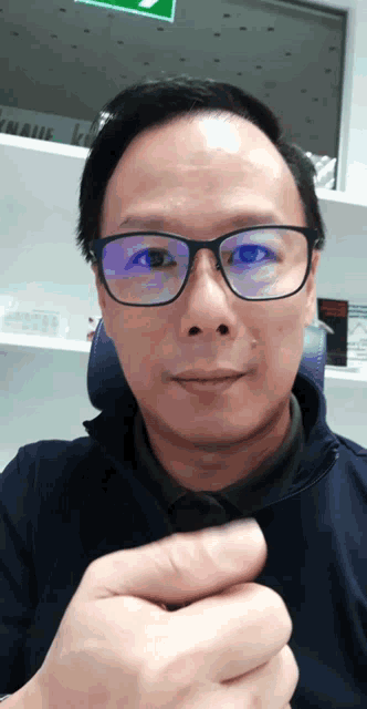 a man wearing glasses and a blue shirt is making a funny face