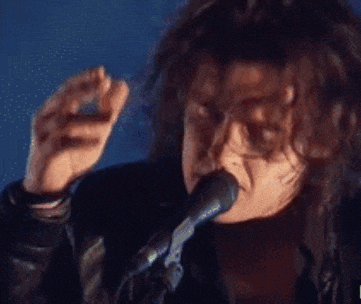 a man singing into a microphone with a cigarette in his hand