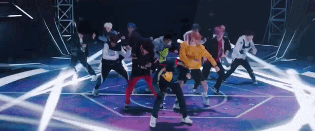 a group of young men are dancing on a stage in a dark room