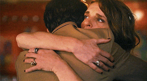 a woman is hugging a man with a ring on her finger .
