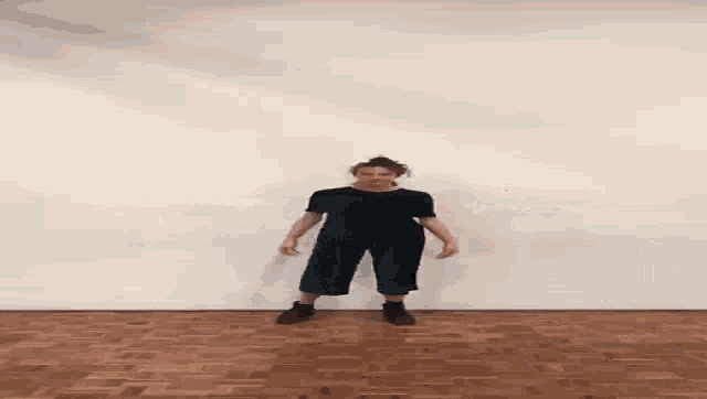 a woman in a black dress is standing on a wooden floor
