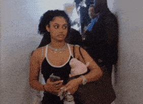 a woman in a black tank top holding a stuffed pig