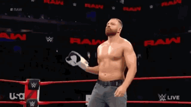 a man without a shirt is standing in a wrestling ring holding a wrestling belt .