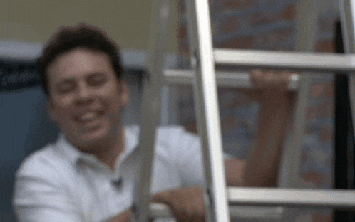 a man in a white shirt is smiling and holding a ladder