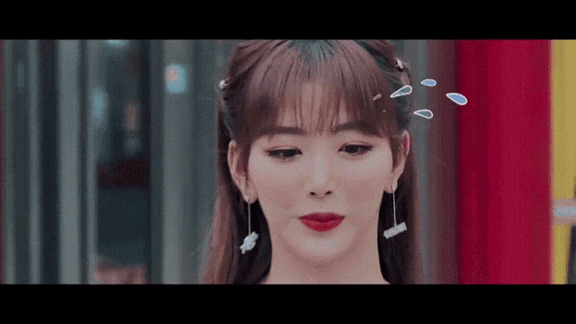 a close up of a woman 's face with red lipstick and earrings .