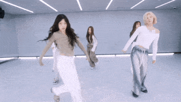 a group of young women are dancing in a room