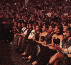 a woman in a black dress is standing in front of a crowd with a sign that says u22