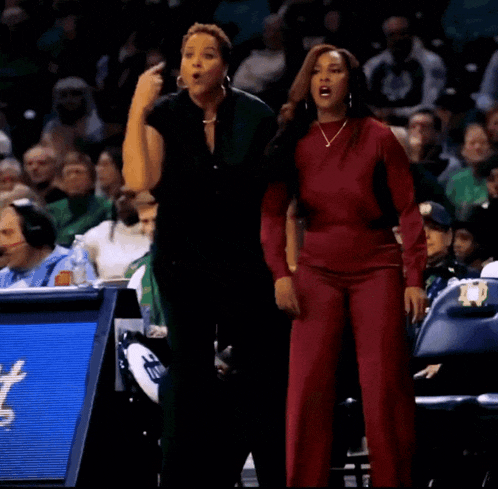 two women are standing on a basketball court and one of them is pointing
