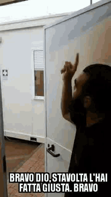 a man with a beard is standing in front of a white door and pointing up .
