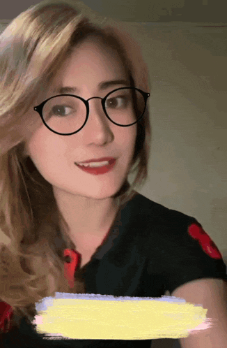 a woman wearing glasses and a black polo shirt is smiling