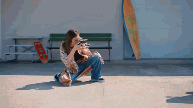 a woman is kneeling down taking a picture with a surfboard behind her