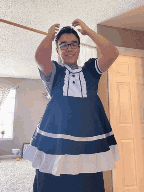 a man wearing glasses and a black and white dress adjusts his hair