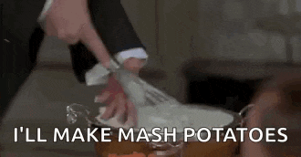 a man in a suit is mixing potatoes in a pot .