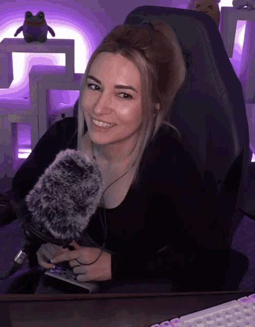a woman sitting in a chair holding a microphone and a remote