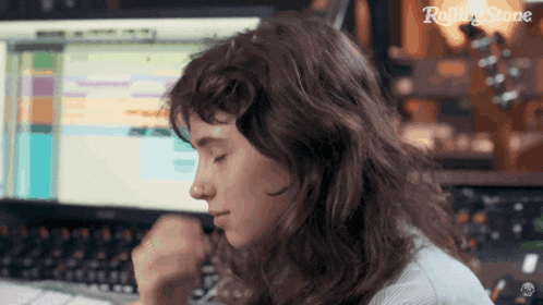 a woman sitting in front of a computer with rolling stone written on the bottom left
