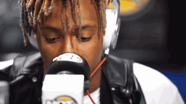 a man is wearing headphones and looking into a microphone that says ' fox ' on it