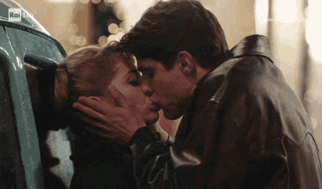 a man and a woman kissing in front of a rai logo