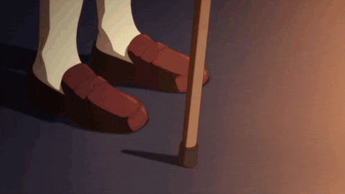 a person wearing a pair of brown shoes standing next to a walking stick