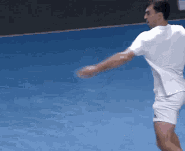 a man is playing tennis on a blue court