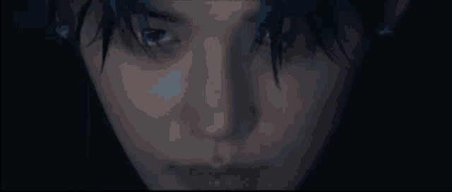 a close up of a person 's face with blue hair and a dark background .