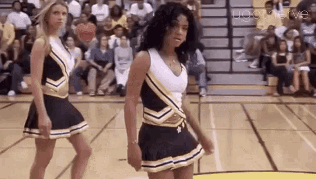 a group of cheerleaders are dancing on a basketball court in front of a crowd .