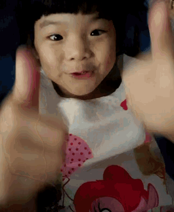 a little girl is giving a thumbs up and wearing a little pony dress