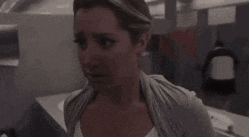 a woman in a gray sweater is looking at the camera