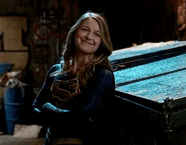 a woman in a superhero costume is standing in front of a dumpster .