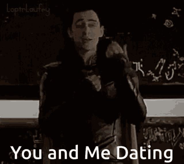 a man in a leather suit is standing in front of a chalkboard and says `` you and me dating '' .
