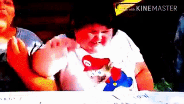 a young boy wearing a mario shirt is sitting at a table with a woman .
